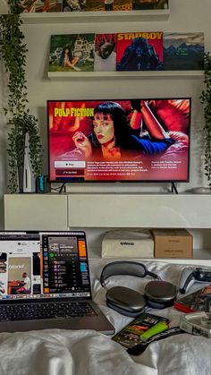 a laptop computer sitting on top of a bed next to a television monitor and headphones