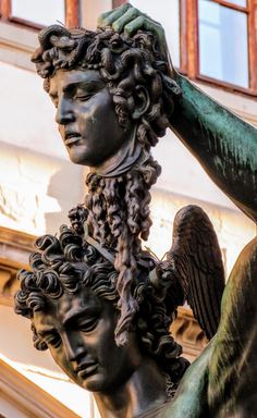 an image of a statue that is holding the head of another sculpture in front of a building