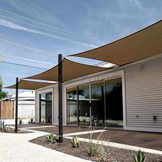 an outdoor patio area with several plants and large awnings on the side of it