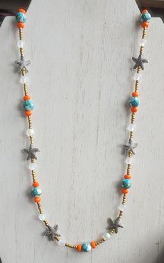 This necklace is made with neon orange beads, clear frosted metallic beads, gold seed beads, speckled turquoise beads, and silver starfish beads. Toggle clasp. Measures 22 inches long end to end. Baseball Necklace, Blue Beaded Earrings, Fish Necklace, Starfish Necklace, Sea Star, Neon Orange, Toggle Clasp, Star Necklace, Turquoise Beads