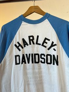 "1980s Harley Davidson blue and white baseball t-shirt. Unworn and Unwashed. Measurements flat: 19\" Pit to Pit 32\" Length All sales final, please ask any questions you have before purchasing! Thank you!" Sporty Blue Cotton Baseball Jersey, Blue Cotton Sporty Baseball Jersey, Blue Cotton Baseball Jersey With Letter Print, Blue Graphic Print Baseball Jersey For Baseball Season, Blue Crew Neck Baseball Jersey With Letter Print, Casual Blue Baseball Jersey With Letter Print, Blue Baseball Jersey With Graphic Print, Blue Graphic Print Baseball Jersey, Blue Cotton Baseball Jersey With Short Sleeves