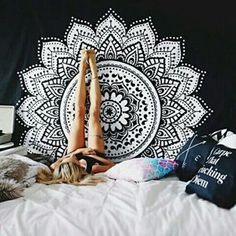 a woman laying on top of a bed in front of a black and white wall