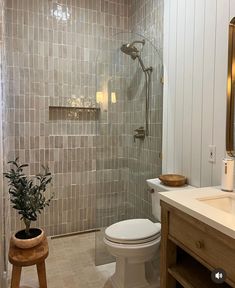 a white toilet sitting in a bathroom next to a walk in shower and wooden stool