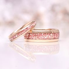 two gold wedding bands with pink glitter on them