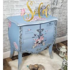 a blue dresser with gold lettering and flowers on it