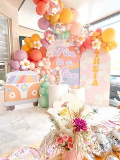 an assortment of balloons and flowers are on display in front of a birthday party backdrop