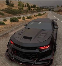 a black sports car is parked on the side of the road with its hood up