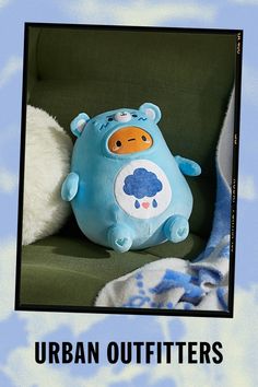 a blue stuffed animal sitting on top of a green chair next to a white pillow