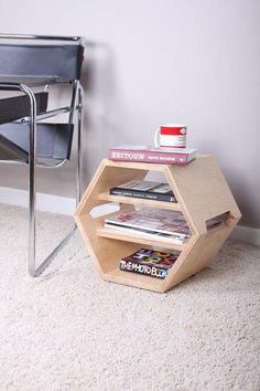 a table with books and magazines on it in front of a chair next to a wall