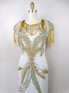 "This is a GORGEOUS gown heavily embellished with sequins, pearls and glass beading. It's in excellent condition! Measurements: Bust - 32\" Waist - 26\" Hips - 36\" Length - 60\" Tag Size - Small This dress comes from a pet-free and smoke-free home. If you would like more info or have any questions, please don't hesitate to ask!" Elegant Embellished Sequin Fabric For Celebration, White Embellished Evening Dress For Wedding, White Rhinestone Evening Dress For Party, Glamorous Beaded Gala Gown, Glamorous White Evening Dress With Rhinestones, White Sequined Party Gown, Floor-length Embellished Sequin Fabric For Weddings, White Glamorous Embellished Evening Dress, Glamorous Beaded Sequin Prom Dress