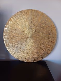 a large gold plate sitting on top of a black table next to a white wall