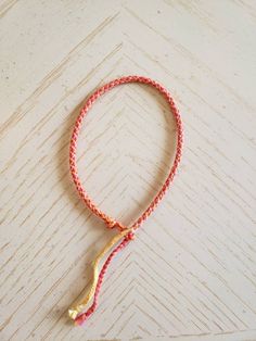 a red and yellow rope with a gold hook on it sitting on top of a wooden table