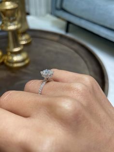 a woman's hand with a diamond ring on top of her finger, in front of a mirror