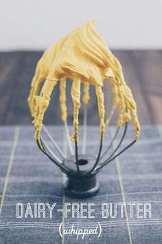 a whisk with yellow icing sitting on top of a table