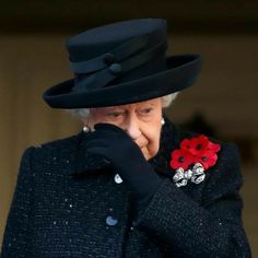 the queen of england is wearing a black hat and holding her hand to her face