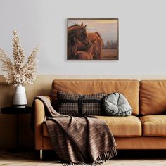 a living room with a brown couch and a painting hanging on the wall above it