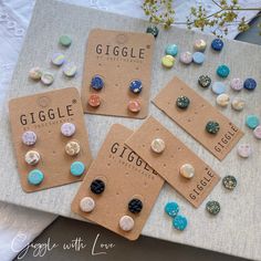 four pairs of earrings are sitting on a table next to some cards with the words giggle