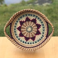 a woven basket sitting on top of a wooden table next to a green grass field