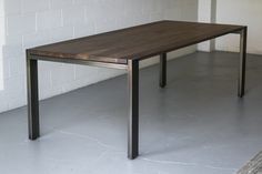 a wooden table sitting on top of a cement floor next to a white brick wall