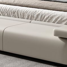 a white leather bench sitting on top of a carpeted floor next to a bed