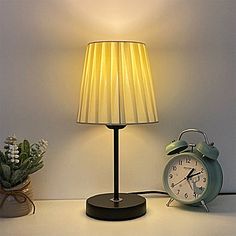 an alarm clock sitting next to a lamp on a table