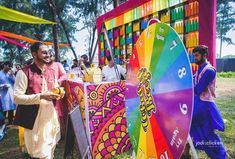 a man standing in front of a colorful display at a festival with people looking on