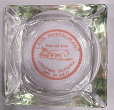 a glass ashtray with an orange and white label on the front that says las restaurant