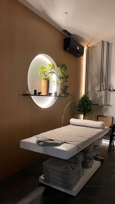 a room with a table and some plants on the wall next to it is a circular mirror