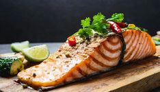 a close up of a piece of fish on a cutting board with broccoli and cucumbers