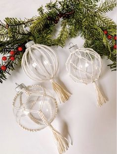 two glass ornaments are sitting on a table next to christmas greenery and red berries