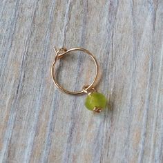 a gold ring with a green bead hanging from it