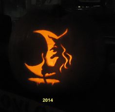 a pumpkin carved to look like a woman's face with the moon in the background