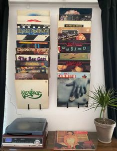 two books are hanging on the wall next to a potted plant and record player