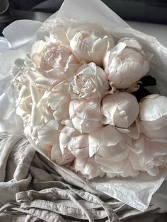 a bouquet of white flowers sitting on top of a bed next to a gray blanket