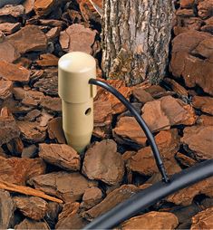 a white water pump sitting on top of rocks next to a tree