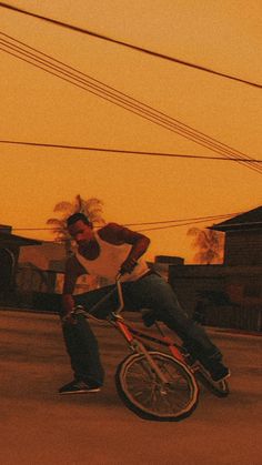 a man riding a bike down the middle of a street at sunset with power lines in the background