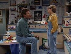 the young man is talking to his friend in front of him on the tv set