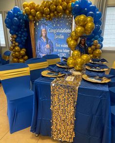 a table with blue and gold decorations, balloons and a sign that says congratulations jayden