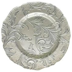 an ornate silver plate with swirls and scrolls on the rim, set against a white background