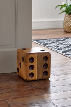 a wooden dice sitting on the floor in front of a door with holes cut into it