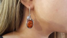 A gorgeous pair of oval drop earrings, featuring a large cognac Amber gemstone with an elegant sterling silver floral frame. Material: Authentic Baltic Amber and 925 sterling silver Dimensions (including closure): 45mm x 16.60mm x 6.70mm ( 1.77 x 0.65 x 0.26 in)  Closure: Lever back Color: Cognac  Finish: Polished A one of a kind pair of elegant earrings featuring beautiful golden Amber gemstones, perfectly shaped and polished. The oxidized sterling silver element boasts a handcrafted floral design that frames the amber perfectly. The oval shape is modern and trendy, whilst their size boast luxury and elegance.  This pair of earrings is a elegant accessory, perfect for a sophisticated and glamorous look. Guaranteed to stand out and bringing out the beauty in every woman. Take a look at our Silver Element, Golden Amber, Dragonfly Jewelry, Silver Flower Earrings, Amber Gemstone, Dragonfly Earrings, Amber Earrings, Amber Ring, Statement Jewellery