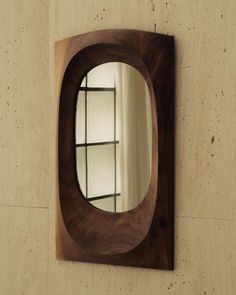 a mirror mounted to the side of a wall next to a wooden shelf with shelves on it