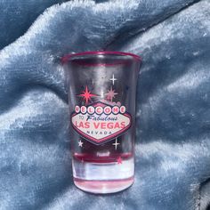 a shot glass with the las vegas sign on it is sitting on a blue blanket