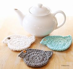 three crocheted birds sitting next to a tea pot