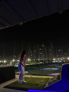 a woman standing on top of a green field with a golf club in the background