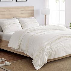 a bed with white comforter and pillows in a room