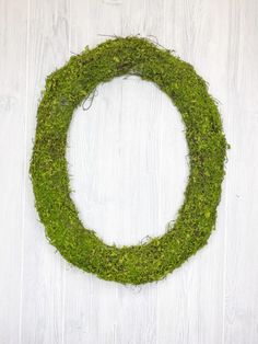 a moss covered wreath on a white wooden background