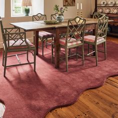 a dining room table with chairs and a rug on the floor