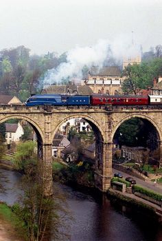 a train traveling over a bridge in the middle of a town next to a river