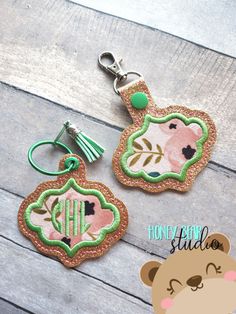 two keychains with an embroidered monogrammed bear and flower design on them